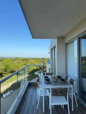 a dining room with a table and chairs on a balcony at Baia Kristal 5I in Estación El Salto