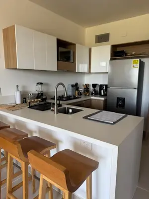 a kitchen with a counter with chairs and a refrigerator at Baia Kristal 5I in Estación El Salto