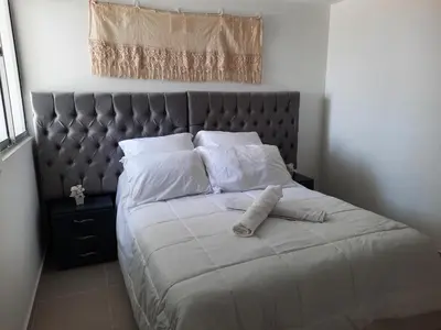 a bed with a gray headboard and white pillows at Apartamento completo in Cartagena de Indias