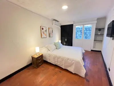 a bedroom with a bed with a night stand and a window at Lovely Duplex with balcony! in Cartagena de Indias