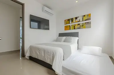 a white bedroom with two beds and a mirror at Beachfront Penthouse 40th Sea View/Historic Center in Cartagena de Indias