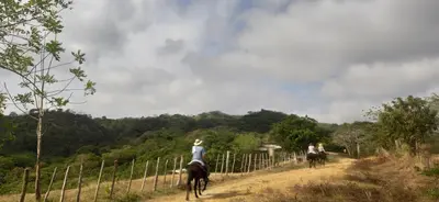 a group of people riding horses down a dirt road at Alquiler de caballos y cabalgatas por el Atlántico in Baranoa