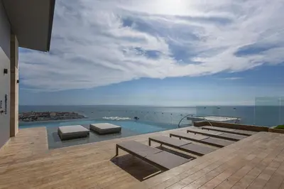 a swimming pool with lounge chairs and the ocean at Cabrero Centro Del Mar - Cerca de la Ciudad Amurallada in Cartagena de Indias