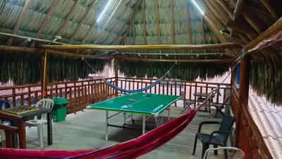 a hammock in a straw hut with a table and chairs at cabaña villa luz in Santa Veronica