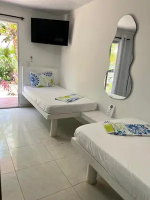 two beds in a room with a mirror and a tv at Hotel Heliopolis in Coveñas