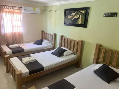 three beds in a room with a painting on the wall at Hotel Georgina in Barranquilla