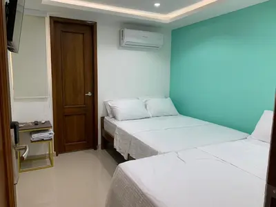 two beds in a room with a blue wall at Hotel Boulevard 58 in Galapa