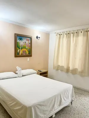 a bedroom with a white bed and a window at Hotel Casa Fátima in Cartagena de Indias