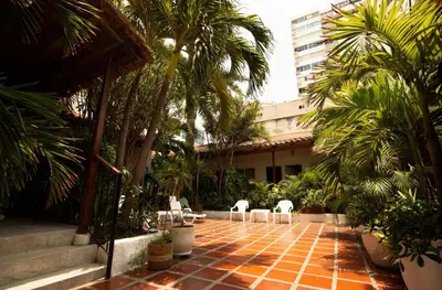 a courtyard with chairs and palm trees and a building at Hotel Casa Fátima in Cartagena de Indias