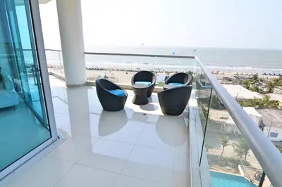 a balcony with three chairs and a view of the beach at Moderno 3 Alcobas Frente a Playa in Cartagena de Indias