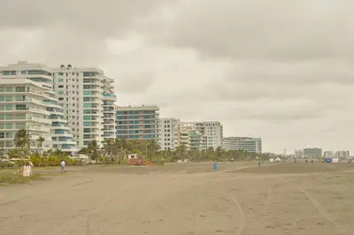 a beach with tall buildings in the background and a person walking on the beach at Moderno 3 Alcobas Frente a Playa in Cartagena de Indias
