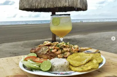 a plate of food with a drink on the beach at Hermosa Cabaña privada cerca a la Playa in Puerto Colombia