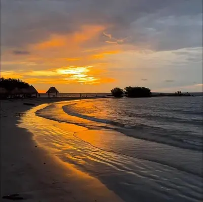 a sunset on a beach with the ocean at La Morada Apartamento in Coveñas