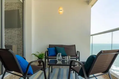 a patio with chairs and a table with a glass table at CB1622 | Suite frente al mar con balcón y piscina in Cartagena de Indias