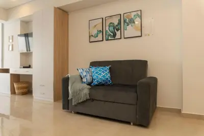 a living room with a brown chair with a blue pillow at Suite Cama King Balcon Vista Hermosa CB634 in Cartagena de Indias
