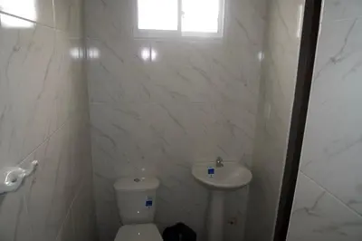 a white bathroom with a toilet and a sink at Hostal Barrio Abajo in Barranquilla