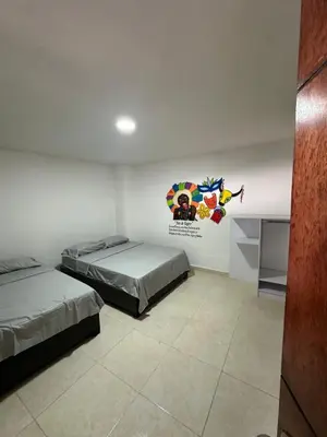 a room with two beds and a painting on the wall at Hostal Barrio Abajo in Barranquilla