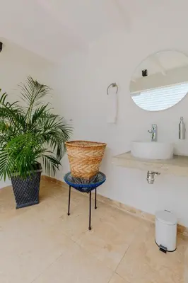 a bathroom with a chair and a plant and a sink at Lux Beach House, Aldaba Selection in Cartagena de Indias