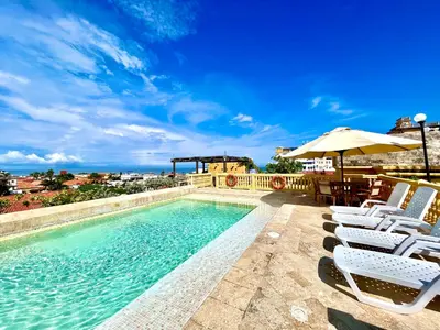a swimming pool with chairs and an umbrella at by Calamari Homes - El Porvenir 401 walled city in Cartagena de Indias