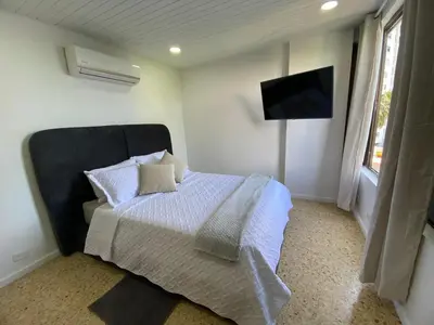 a bedroom with a bed and a flat screen tv at Acogedor Apartamento cerca al Mar in Cartagena de Indias