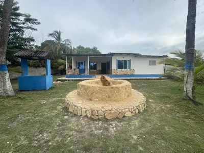 a dog sitting in a sand pit in front of a house at Cabaña Mery frente al mar in San Antero
