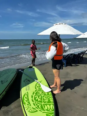 two people on the beach with surfboards and an umbrella at casa kite school in Cartagena de Indias