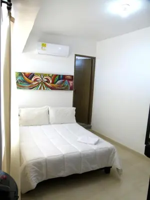 a bedroom with a white bed with a painting on the wall at Hotel Central in Sincelejo