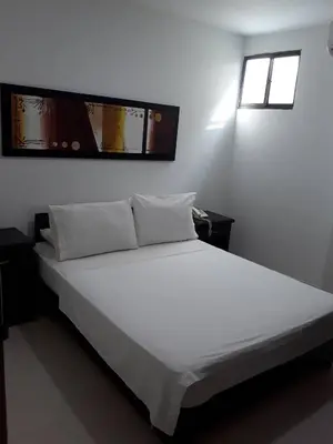 a white bed in a room with two windows at Hotel Central in Sincelejo