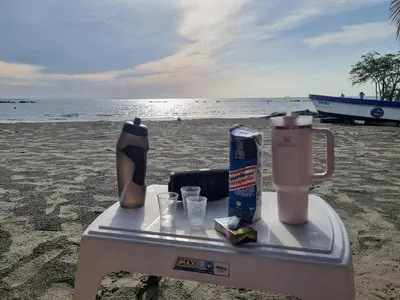 a table on the beach with a drink on it at Espectacular apto frente al mar in Coveñas