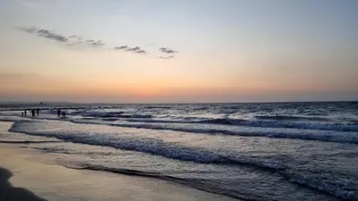people walking on the beach at sunset at Espectacular apto frente al mar in Coveñas