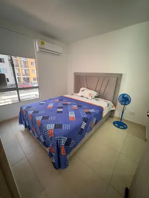 a bedroom with a bed with a quilt and a fan at Apartamento norte de Barranquilla in Barranquilla
