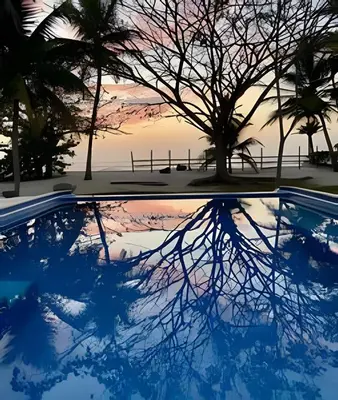 a pool with trees and a sunset in the background at Casa de playa Manglares in Tolú