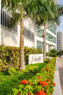 a sign in front of a building with palm trees and flowers at Paraíso Costero Apartamento de Lujo con Vista Directa al Mar in Cartagena de Indias