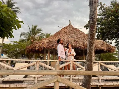 a man and a woman standing in front of a hut at Casa de playa rústica en Tolú in San Silvestre