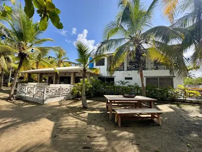 a picnic table in front of a house with palm trees at Casa de playa rústica en Tolú in San Silvestre