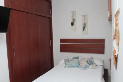 a bedroom with a bed and a wooden cabinet at Encantador Apartamento El Laguito Bocagrande in Cartagena de Indias