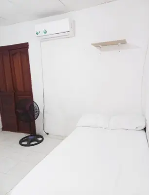 a room with a bed and a door and a chair at Apartamento hostal oasis 2 in Puerto Colombia