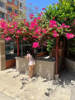a woman standing next to a wall with pink flowers at the best view of Barranquilla in Barranquilla