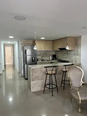 a kitchen with a counter with stools and a refrigerator at Acogedor y Moderno Apartamento en Barranquilla in Barranquilla
