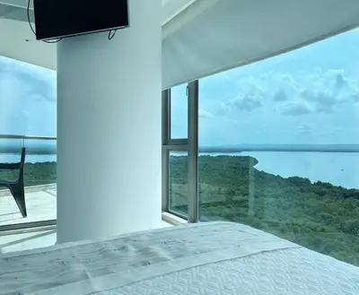 a bedroom with a bed and a large window at Beachfront Apartment at Radisson Hotel in Cartagena de Indias