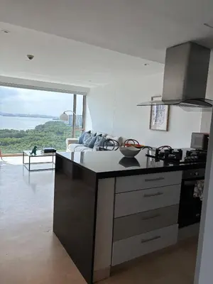 a kitchen with a counter top with a couch in the background at Beachfront Apartment at Radisson Hotel in Cartagena de Indias