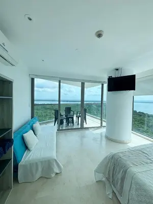a bedroom with a bed and a television and a table at Beachfront Apartment at Radisson Hotel in Cartagena de Indias