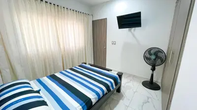 a bedroom with a blue and white striped bed and a fan at Casa Elena in Tolú