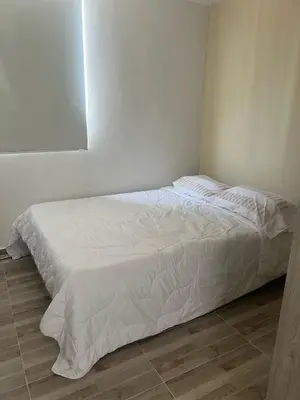 a bed in a bedroom with a white bedspread at Margarita's apt in Barranquilla