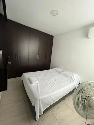 a bedroom with a bed with white sheets and wooden cabinets at Apto en Alameda del rio cunjunto ruiseñor 1 piso 5 in Barranquilla