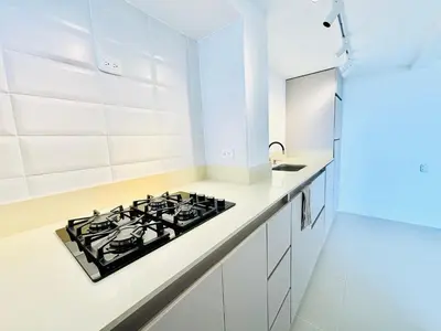 a white kitchen with a stove top oven next to a counter at Splendid condo with a sea view in Puerto Colombia