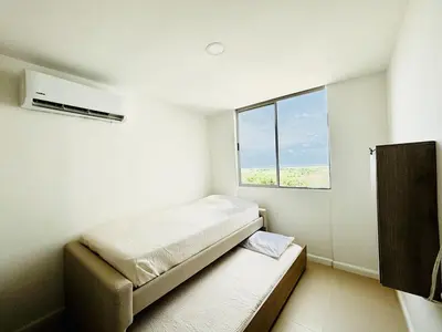 a small bedroom with a bed and a window at Splendid condo with a sea view in Puerto Colombia
