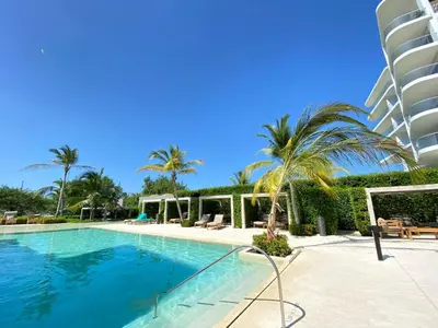 a swimming pool with palm trees and a building at Apartamento en Playa Manzanillo in Cartagena de Indias