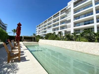 a swimming pool with chairs and a building at Apartamento en Playa Manzanillo in Cartagena de Indias