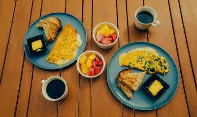 a table with two plates of breakfast foods and cups of coffee at Viajero Cartagena - Getsemaní Hostel in Cartagena de Indias